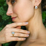 Model wearing blue topaz pendant styled with hand on chest showing fine chain and stone clarity