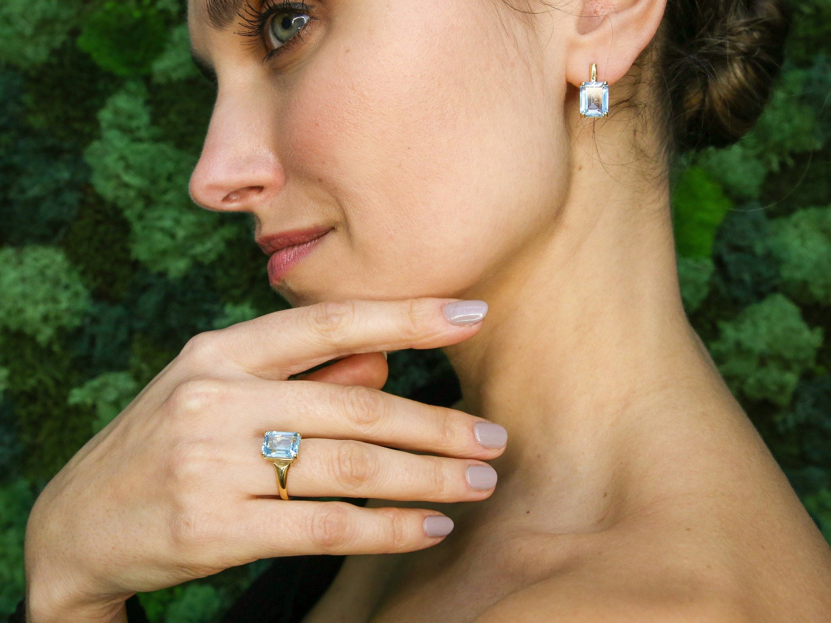 Model wearing blue topaz pendant styled with hand on chest showing fine chain and stone clarity