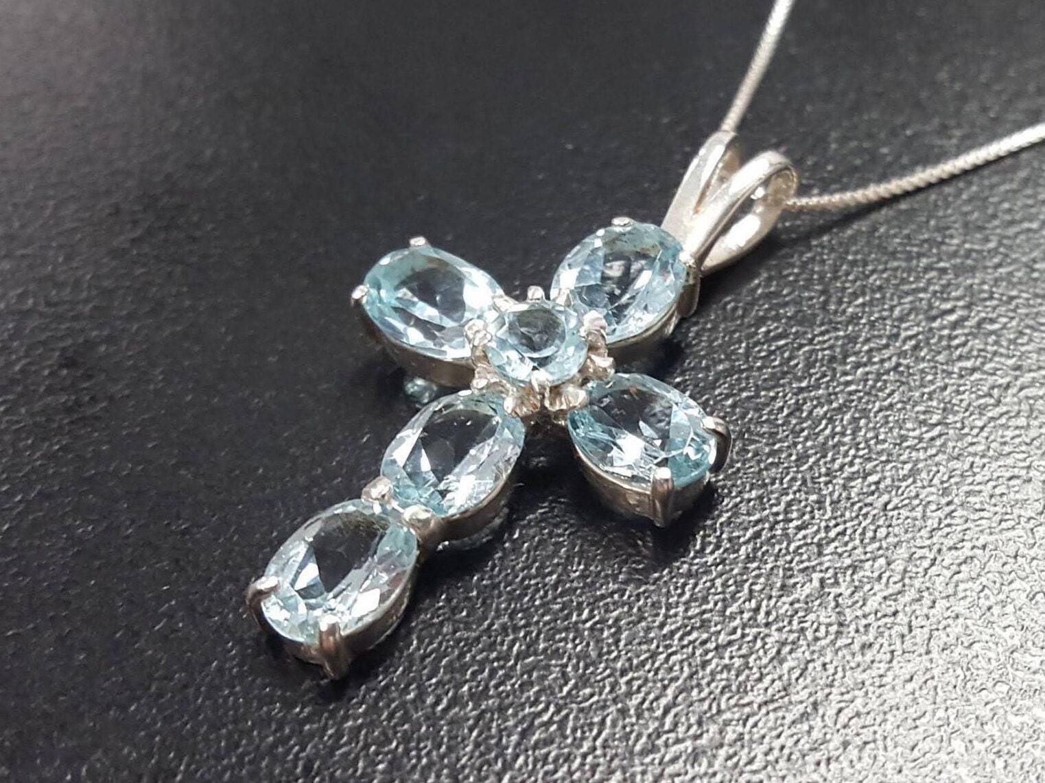 Blue Topaz cross necklace highlighting December birthstone magic