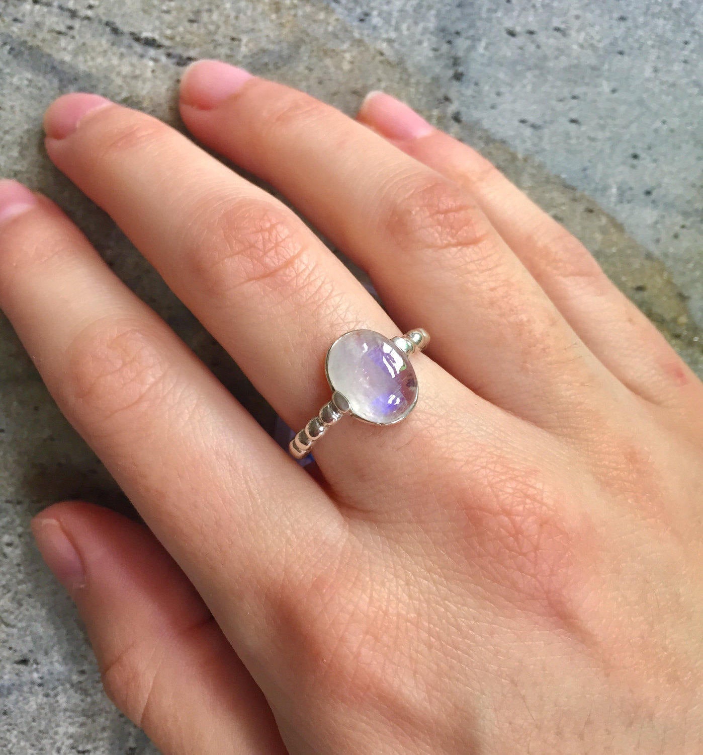 Natural Rainbow Moonstone ring worn on the middle finger, lit with natural light and styled for effortless boho elegance, ideal with breezy neutrals.