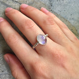 Natural Rainbow Moonstone ring worn on the middle finger, lit with natural light and styled for effortless boho elegance, ideal with breezy neutrals.