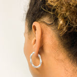 Close-up of woman showcasing solid 925 sterling silver hoop earrings in ear