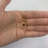 Dainty gold halo pendant with natural garnet January birthstone shown in a hand for scale – handcrafted red gemstone necklace