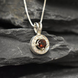 Dainty round garnet necklace, in a round cut and prong setting, with small CZ diamonds.