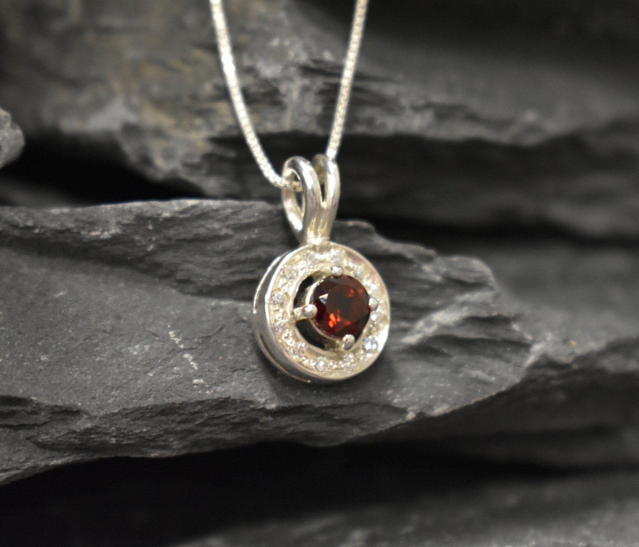 Dainty round garnet necklace, in a round cut and prong setting, with small CZ diamonds.