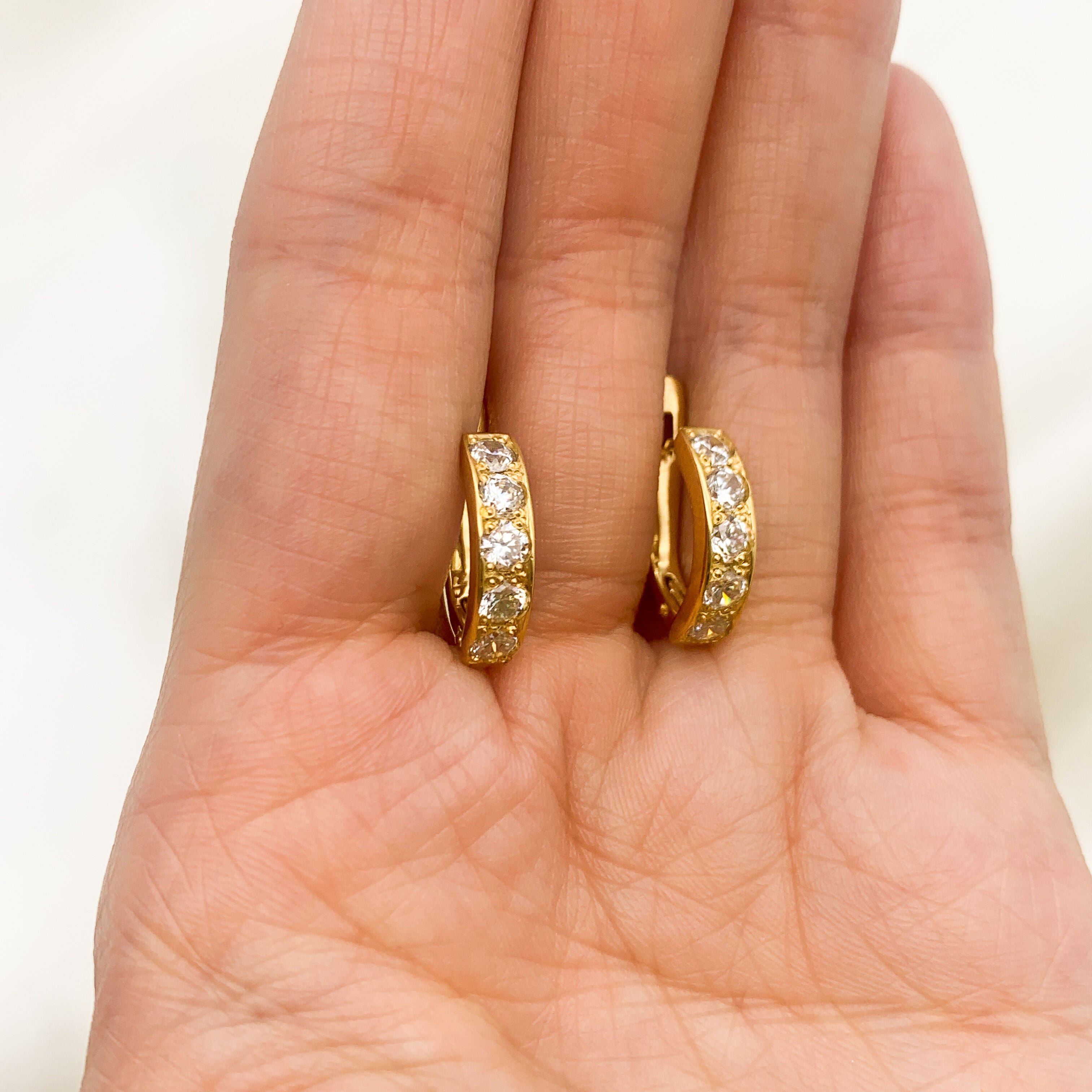 18k Yellow gold plated earrings with Diamond April birthstone in round cut and prong setting. Half hoop earrings resting in an open palm, ideal gift for her or anniversary present.