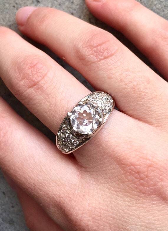 Diamond ring on middle finger styled with soft nude nails, complementing casual to formal wear effortlessly.