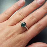 Woman wearing emerald silver ring showing vibrant blue stone and elegant gold band on finger