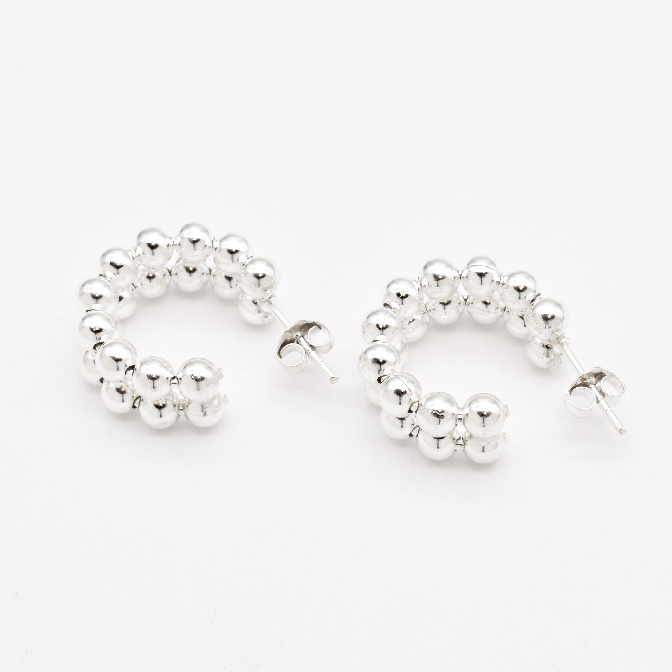 Flat lay of solid 925 sterling silver beaded hoop earrings on white surface
