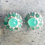 A serene landscape featuring rolling hills, a bright blue sky, and fluffy white clouds beneath a warm sunlight glow.