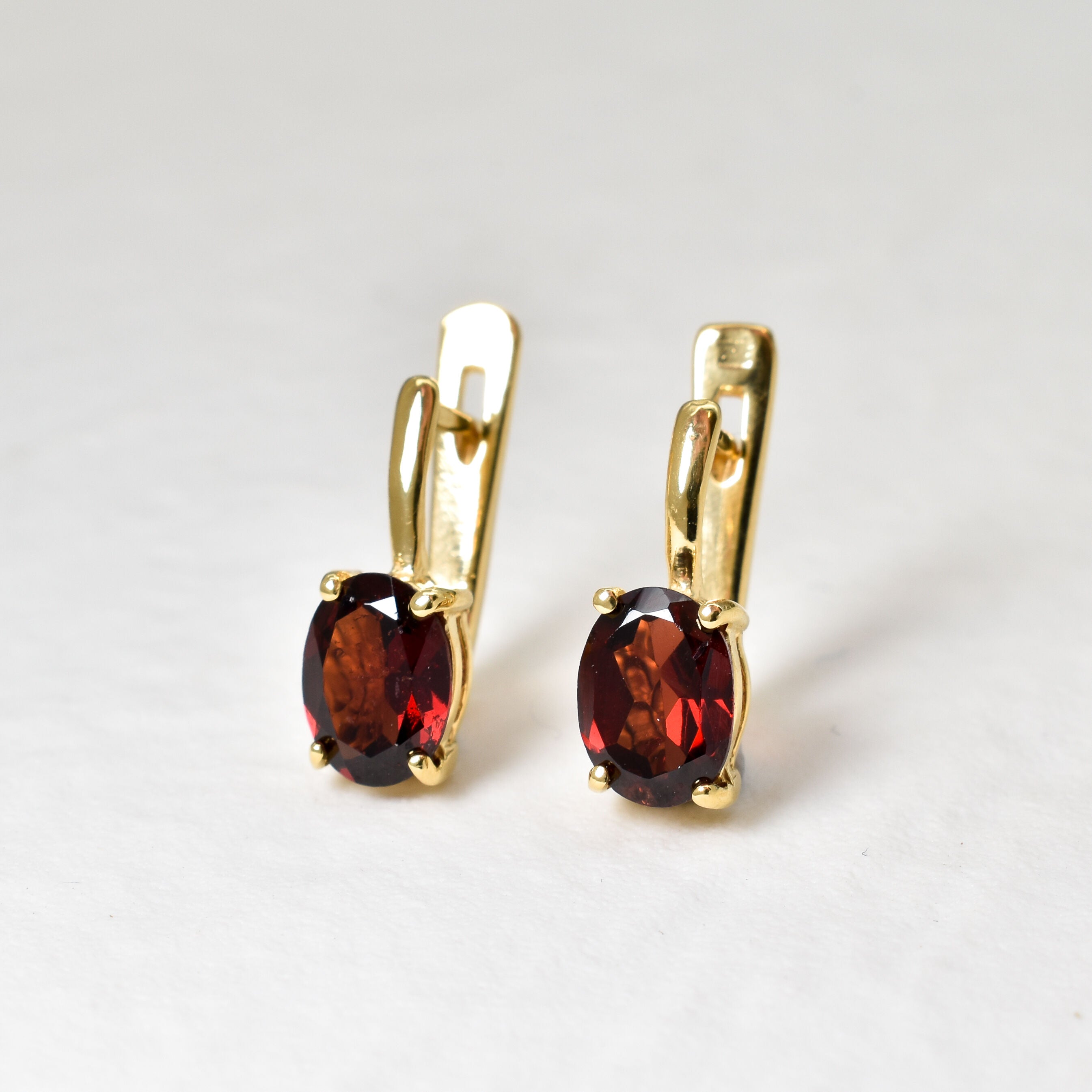 Garnet drop earrings with 8x6mm diamond cut gemstones in polished gold, shown front-facing with lever back clasp
