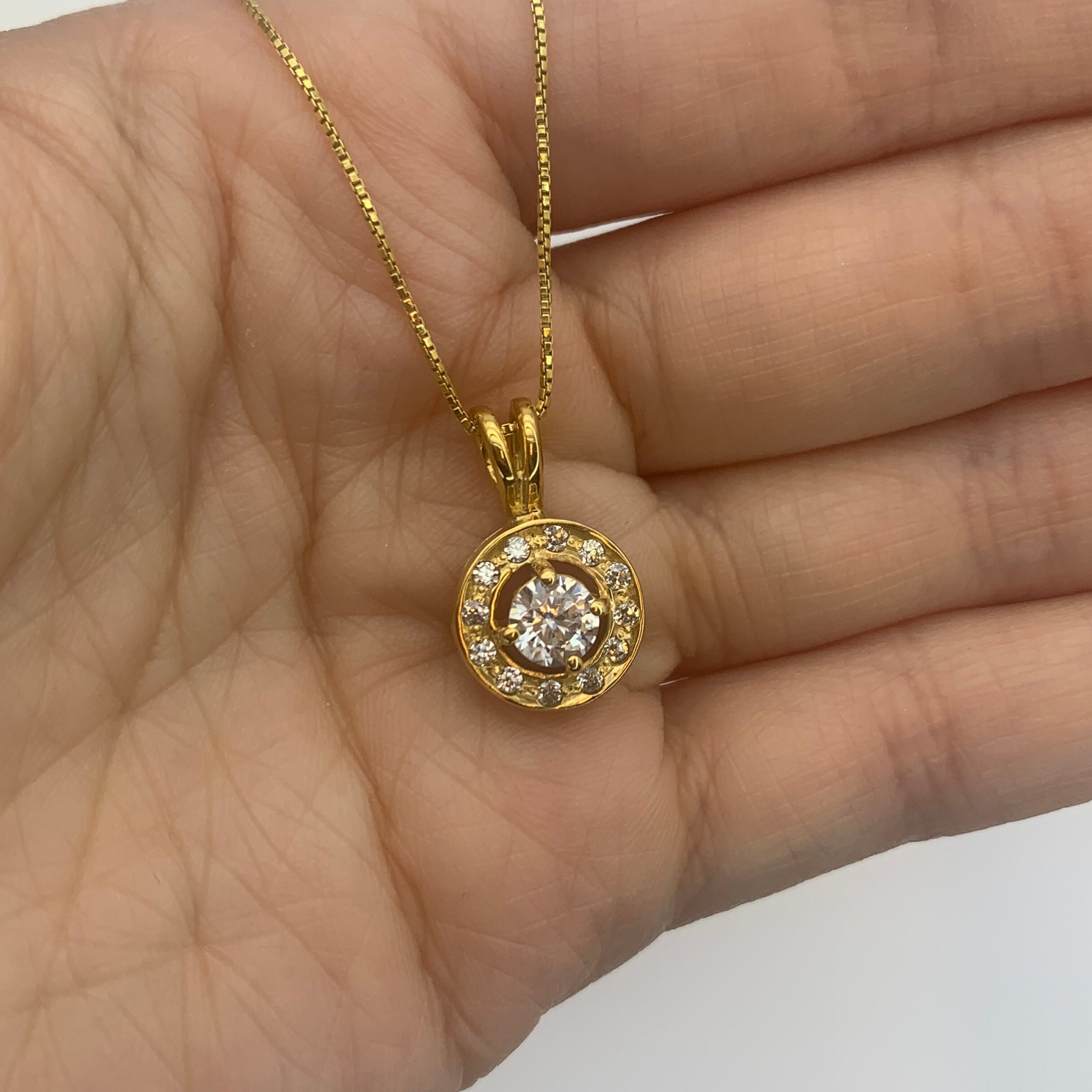 18k Yellow gold plated necklace with Diamond April birthstone in diamond cut and prong setting, dainty round diamond pendant resting in an open palm.
