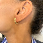 Woman wearing Fishbone Earrings set in 18k Yellow Gold over solid 925 sterling silver. Hinged Hoop Earrings for casual wear, and can also be worn as a statement piece jewelry.