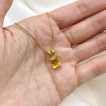 Gold necklace with a natural citrine pendant displayed in an open palm – yellow gemstone jewelry for November, in emerald cut and prong setting. For joy, abundance, and confidence