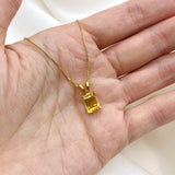 Gold necklace with a natural citrine pendant displayed in an open palm – yellow gemstone jewelry for November, in emerald cut and prong setting. For joy, abundance, and confidence