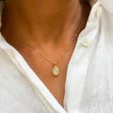 Woman in a white linen shirt, wearing natural opal pendant set in 18k yellow gold over sterling silver. Fire opal necklace ideal gift for her, perfect for wearing solo, and layering necklaces. 