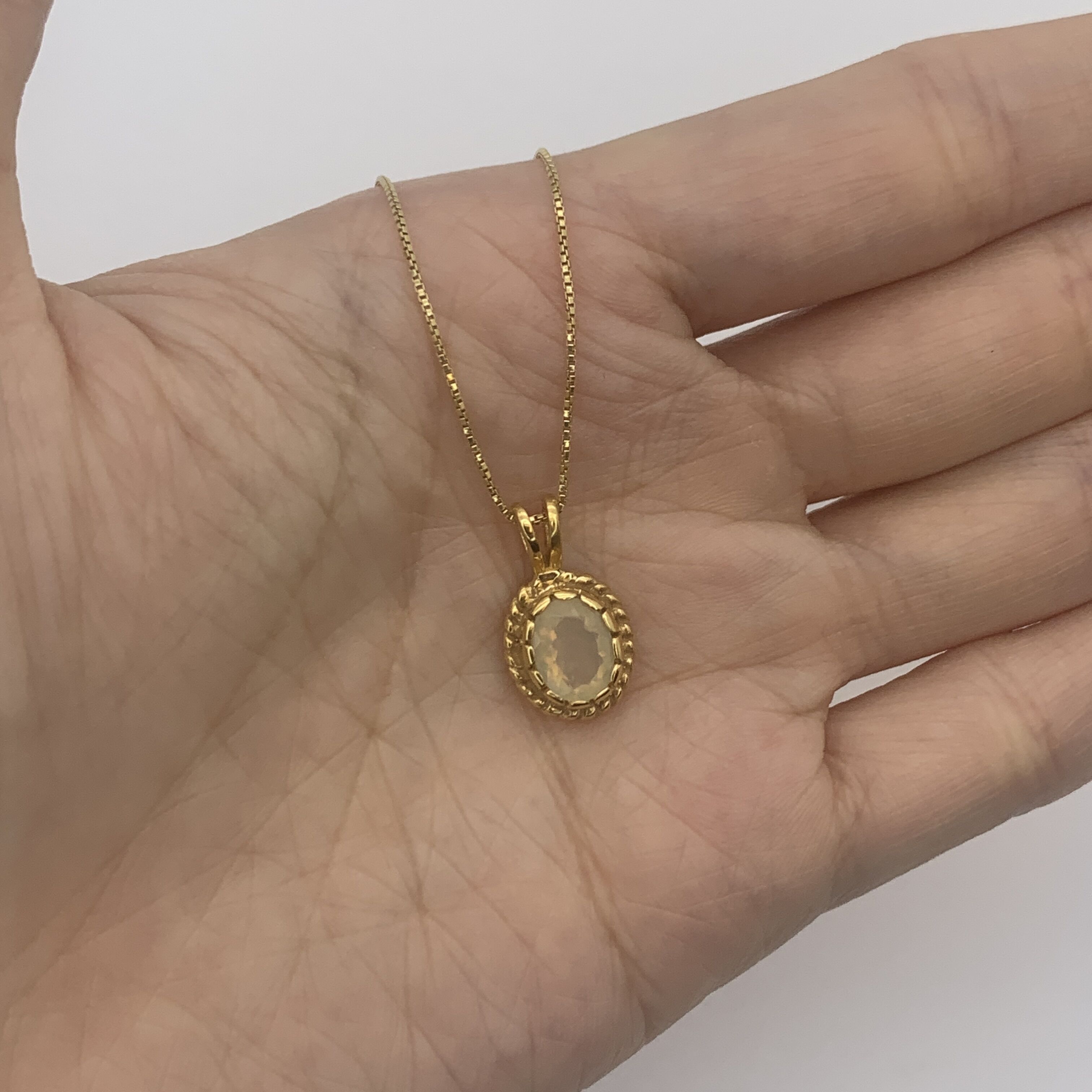 18k yellow gold pendant with natural fire opal October birthstone shown in a hand for scale – handcrafted solitaire necklace