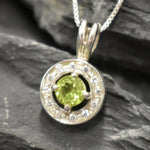 Natural Peridot surrounded by sparkling CZ stones in a round pendant design, known for emotional clarity and perfect for milestone birthdays or anniversaries.