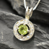 Natural Peridot surrounded by sparkling CZ stones in a round pendant design, known for emotional clarity and perfect for milestone birthdays or anniversaries.