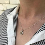 Natural Peridot Pendant resting on skin with buttoned blouse, showcasing timeless gemstone elegance, perfect as a thoughtful birthday gift or gemstone keepsake.