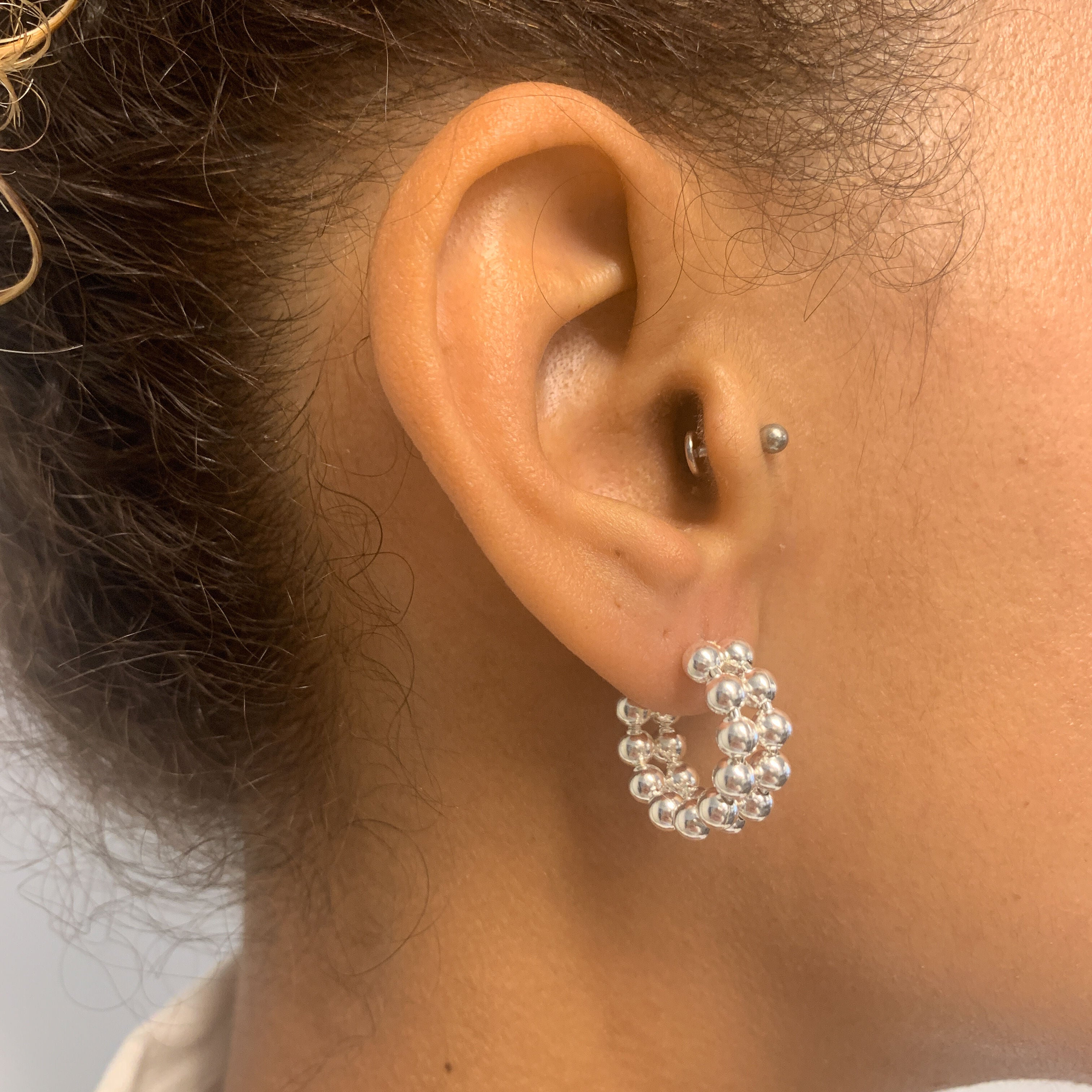 Side view of woman wearing solid 925 sterling silver beaded hoop earrings