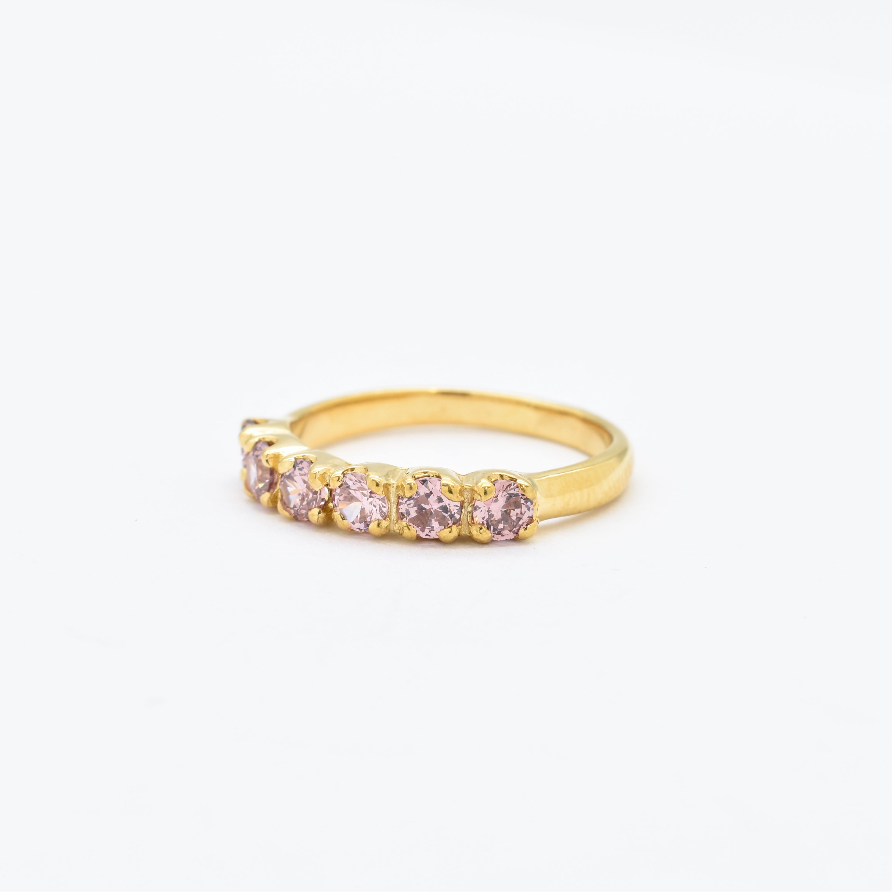Close-up side view of morganite ring with diamond cut stones in gold band