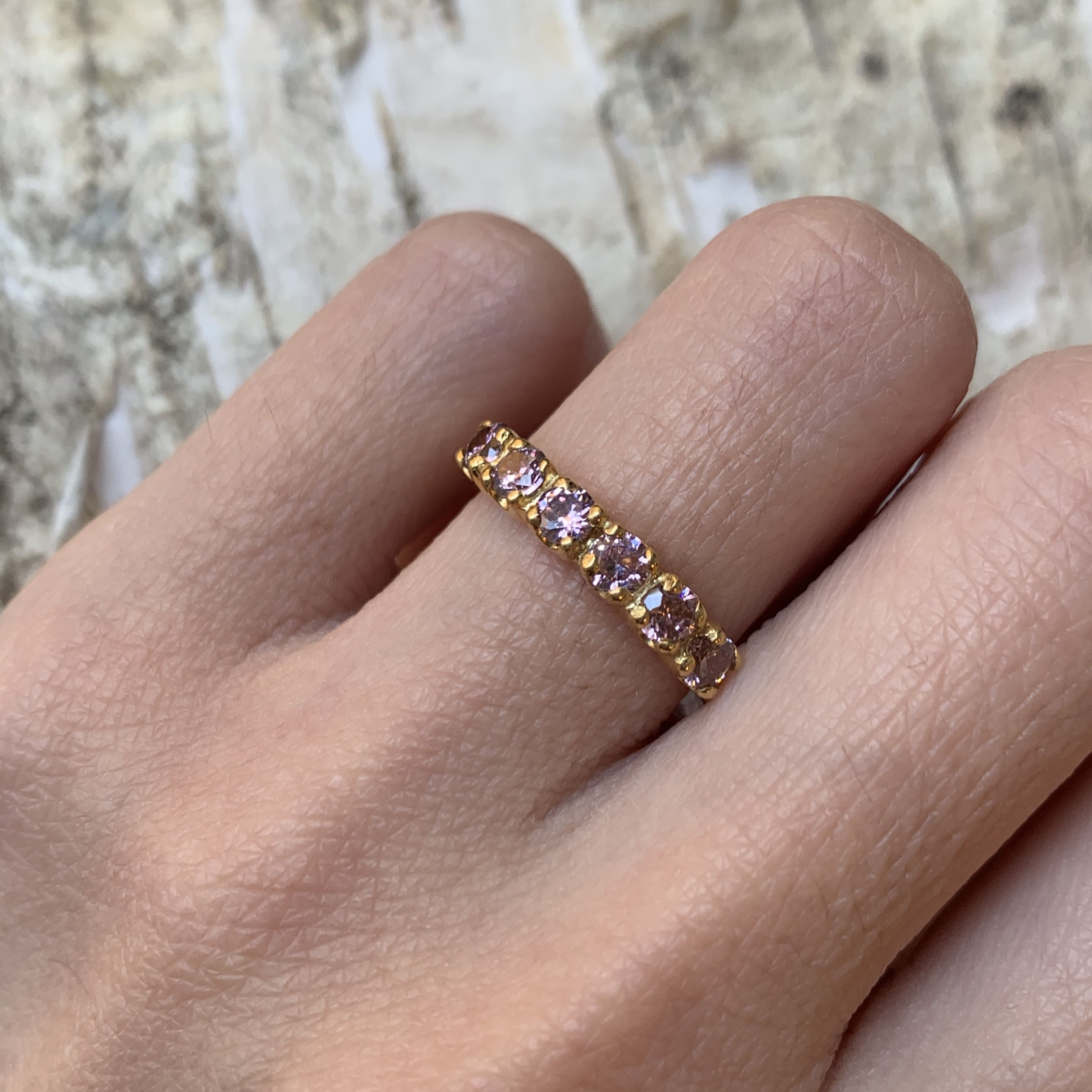 Woman wearing morganite gold ring showing sparkling pink stones on finger
