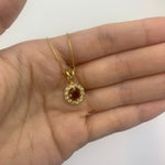 Natural garnet January birthstone pendant in 18k gold resting in an open palm – dainty necklace for size reference.
