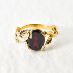 Natural Garnet January birthstone ring set in 18k yellow gold vermeil over solid 925 sterling silver, in prong setting, and leaf-inspired band. Red solitaire gemstone ring promotes energy, passion, and safety in travel. Often associated with love and commitment. Perfect for special occasions, and ideal birthday present