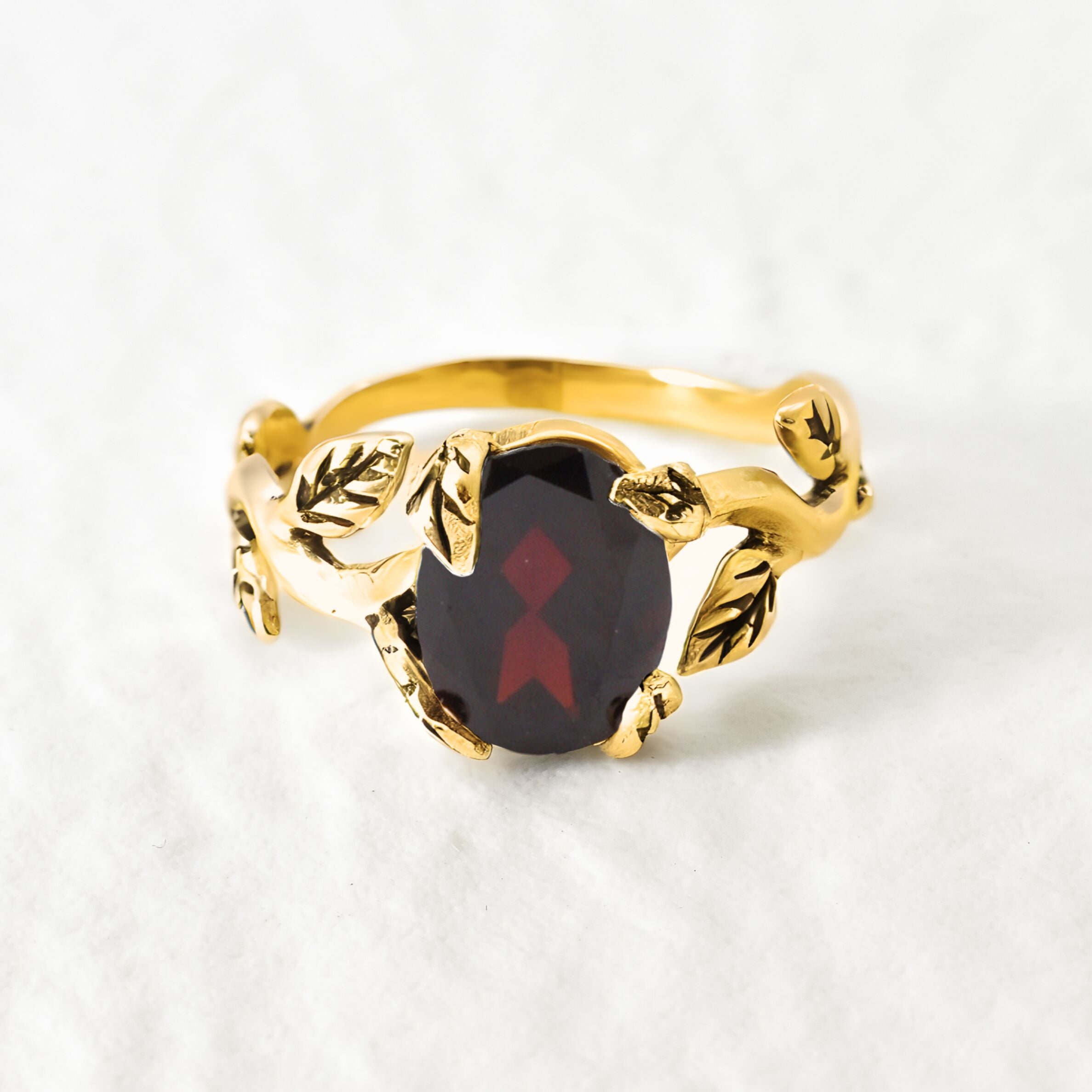 Natural Garnet January birthstone ring set in 18k yellow gold vermeil over solid 925 sterling silver, in prong setting, and leaf-inspired band. Red solitaire gemstone ring promotes energy, passion, and safety in travel. Often associated with love and commitment. Perfect for special occasions, and ideal birthday present