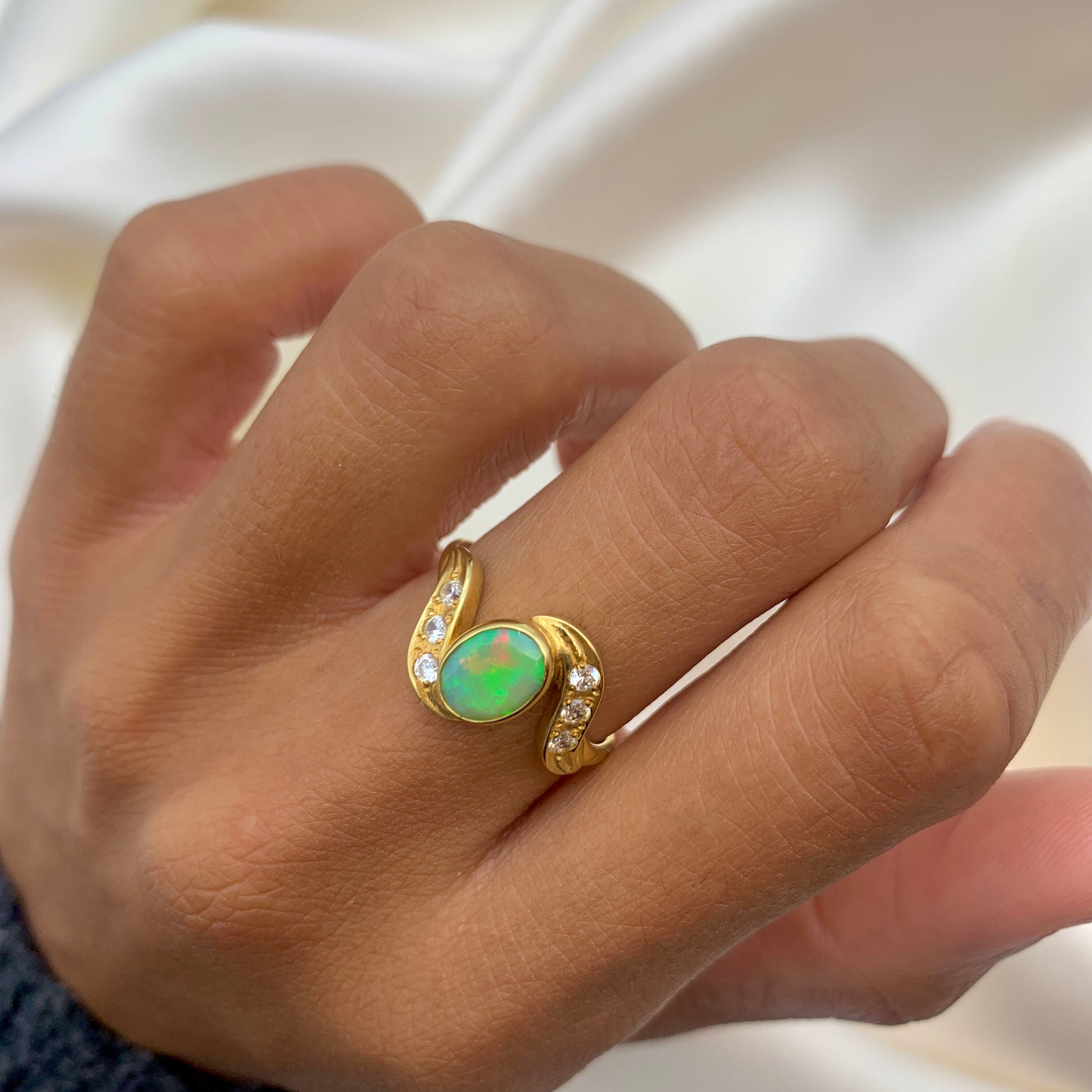 Vintage Opal Ring in a bezel set gold wave design with flashes of rainbow and fire colors, accented by sparkling CZ Diamonds on each curve. Opal is believed to inspire creativity, hope and emotional balance, making it a meaningful October birthstone gift for anniversaries, engagements, weddings and special celebrations.