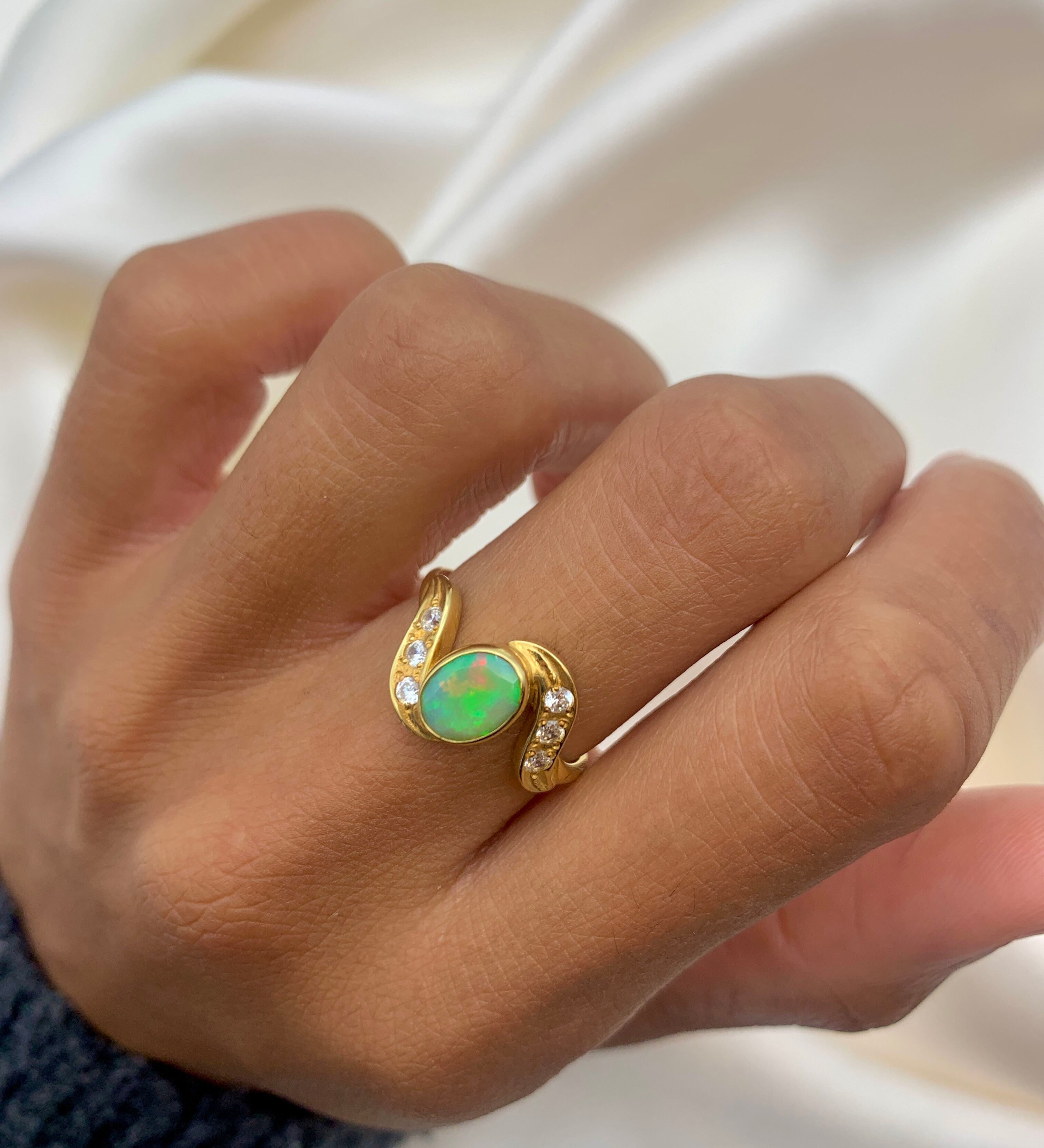 Vintage Opal Ring in a bezel set gold wave design with flashes of rainbow and fire colors, accented by sparkling CZ Diamonds on each curve. Opal is believed to inspire creativity, hope and emotional balance, making it a meaningful October birthstone gift for anniversaries, engagements, weddings and special celebrations.