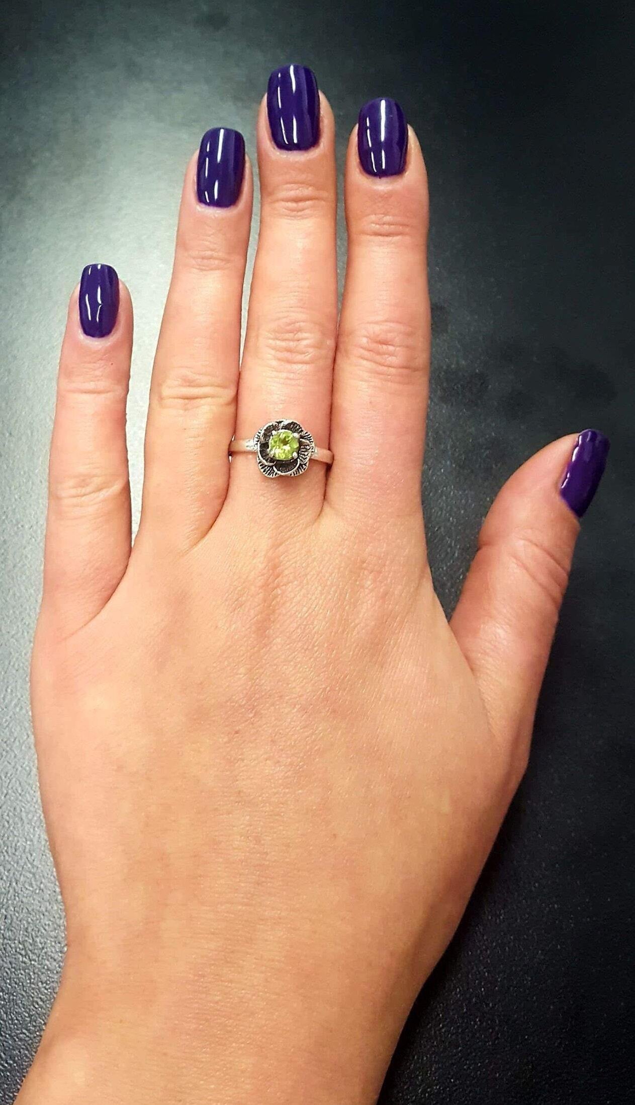 Peridot gemstone ring on middle finger, paired with clean nail look for a casual yet earthy style perfect for everyday wear.