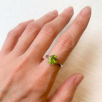 Peridot ring styled on hand with soft-toned manicure, versatile for office wear or sophisticated day looks.