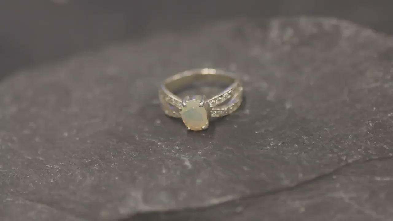 Opal Ring with split shank band and CZ pave setting showing flashes of fire colors, designed as elegant fine jewelry. Known for its emotional healing and creativity benefits, Opal is also the October birthstone and a thoughtful gift for birthdays or anniversaries. Perfect to wear at weddings, romantic dinners, and special evening celebrations.