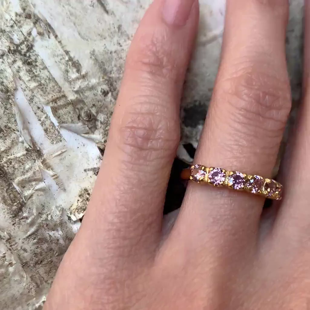 Close-up of morganite ring worn on hand showing delicate pink stones and gold band