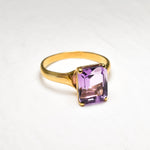 Yellow gold plated ring with genuine amethyst February birthstone in emerald cut and prong setting. Bold solitaire ring ideal for special events, and personalized gift. Encourages calmness, spiritual growth, and emotional balance. For peace, clarity, intuition