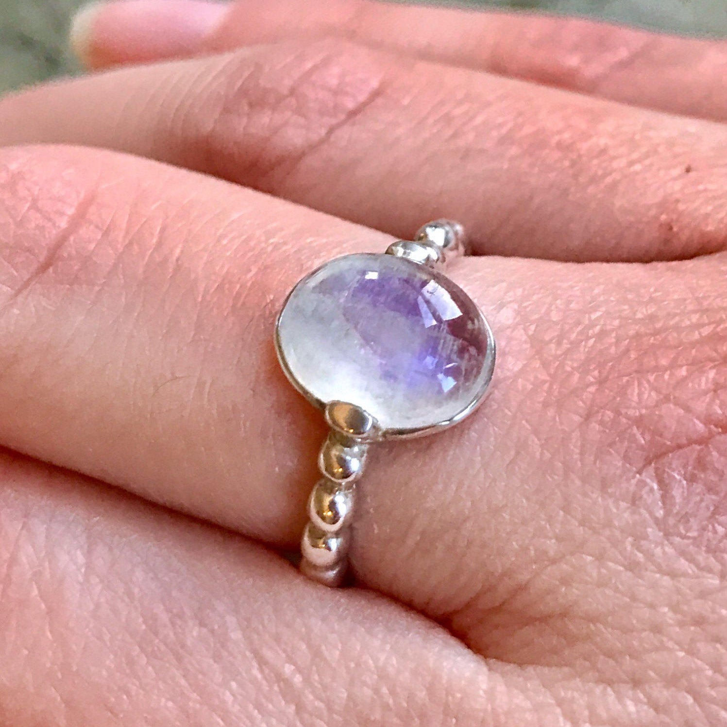 Rainbow Moonstone ring styled on the middle finger, paired with nude polish for a soft, grounded look—perfect for casual outfits and quiet weekends.