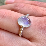 Rainbow Moonstone ring styled on the middle finger, paired with nude polish for a soft, grounded look—perfect for casual outfits and quiet weekends.