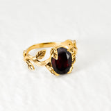 Red Garnet January birthstone ring set in 18k yellow gold vermeil over solid 925 sterling silver, in prong setting, and leaf-inspired band. Natural solitaire gemstone ring promotes energy, passion, and safety in travel. Often associated with love and commitment. Perfect for special occasions, and ideal birthday present
