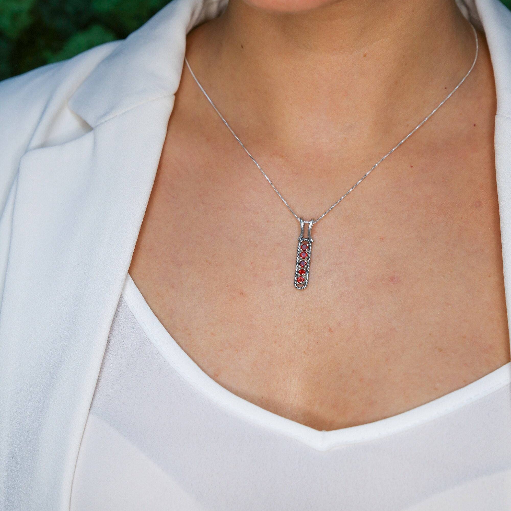 Ruby bar pendant necklace styled with a white blazer and scoop top, ideal for professional settings, symbolic of courage and elegance, great for anniversaries or empowering gifts.
