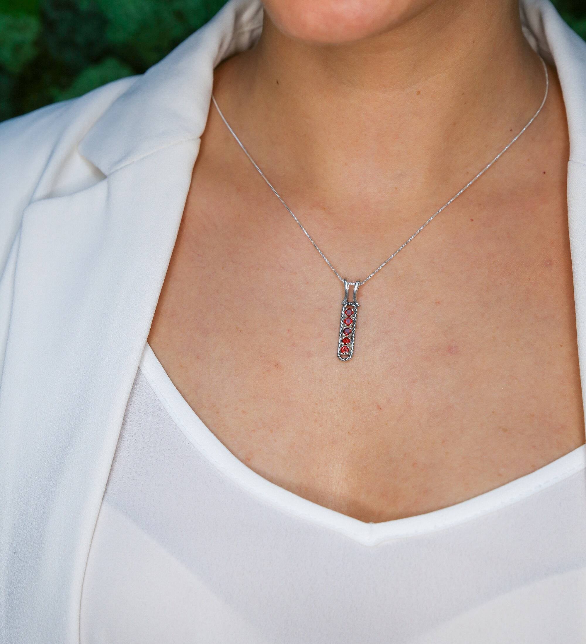 Ruby bar pendant necklace styled with a white blazer and scoop top, ideal for professional settings, symbolic of courage and elegance, great for anniversaries or empowering gifts.
