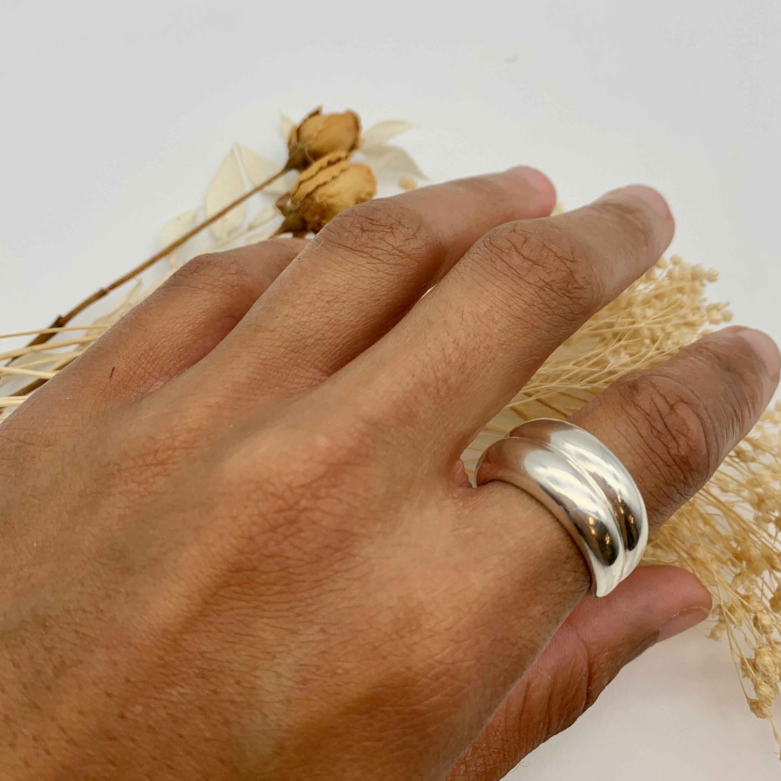 Hand model wearing a solid 925 sterling silver band ring, paired with neutral accessories.