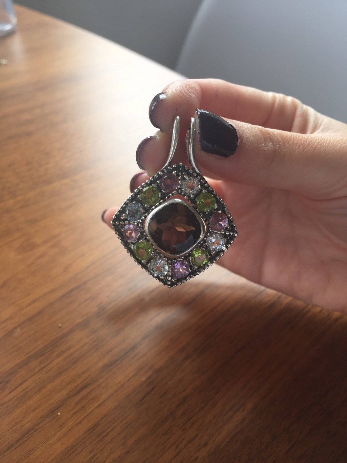 Multistone pendant held gently to show color range, pairs best with dark manicures and neutral-toned outfits for dramatic flair